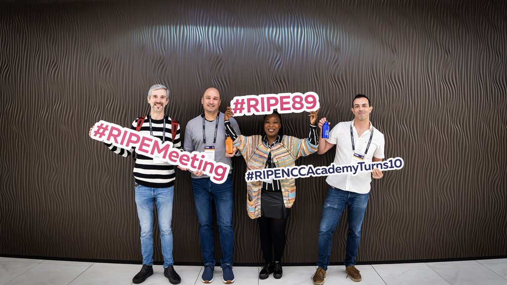 People stand with signs that say RIPE Meeting and RIPE 89.