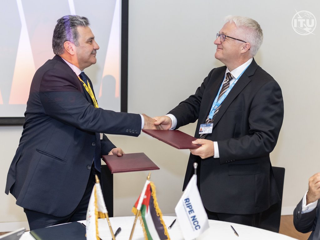 Two men stand and shake hands.